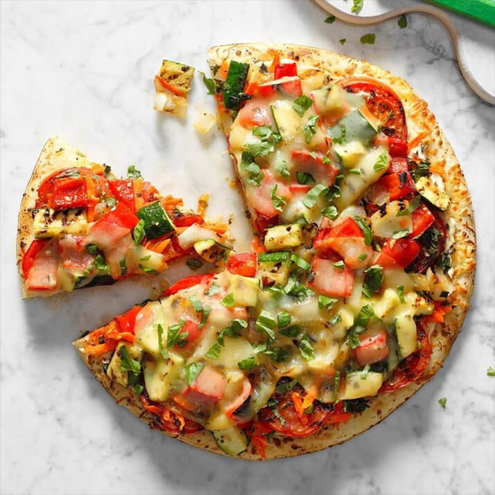 Grilled veggie pizza topped with peppers, zucchini, and tomatoes.