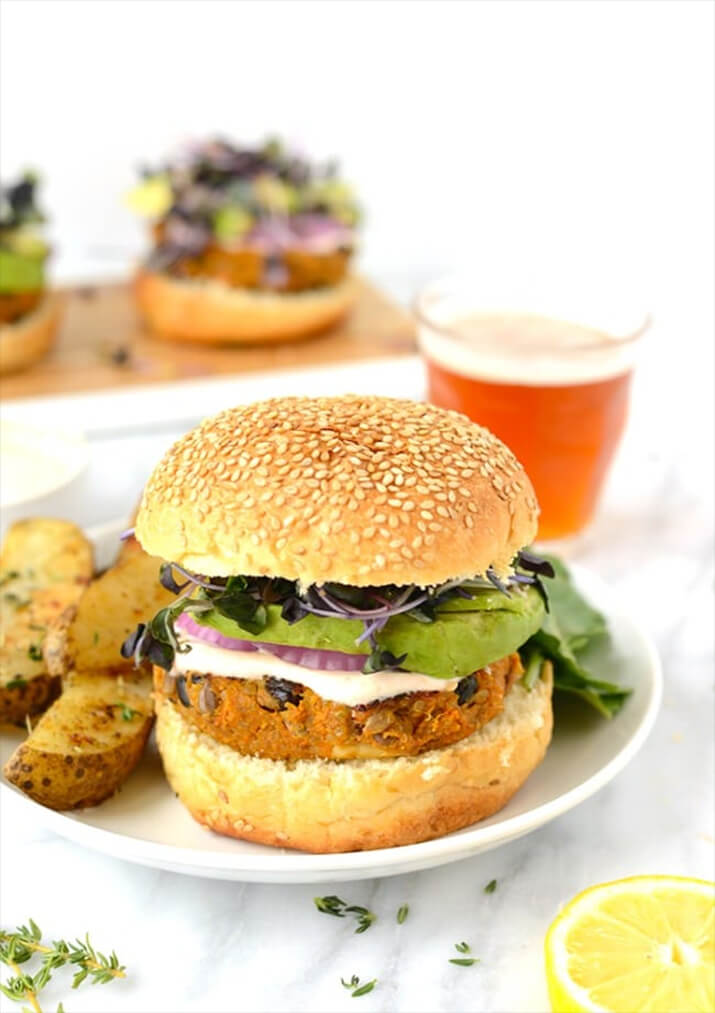 Sweet potato black bean burger topped with red onion and spinach on a sesame bun.