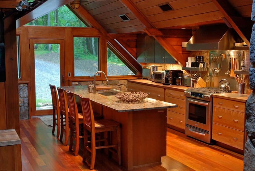An A-frame cabin with exposed ceiling beams and a modern stainless steel kitchen.