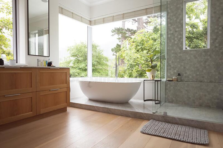 Bathroom with large windows overlooking green trees.