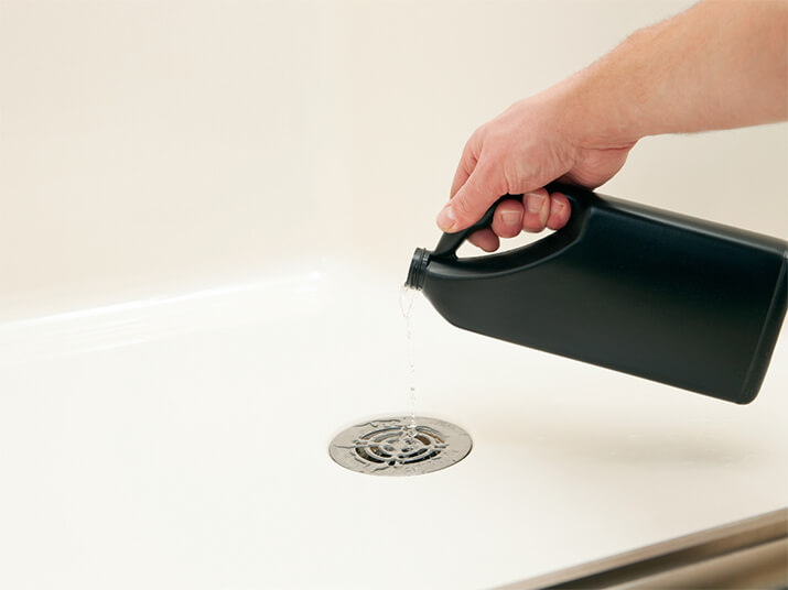 Image six: A black, unlabeled bottle of commercial unclogging solution is poured down a drain.