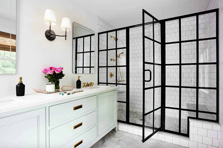 Clean white bathroom with a glass-paneled shower door with black framing.