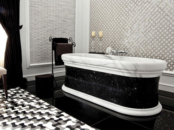 The centerpiece of this bathroom is a black and white marble freestanding tub.