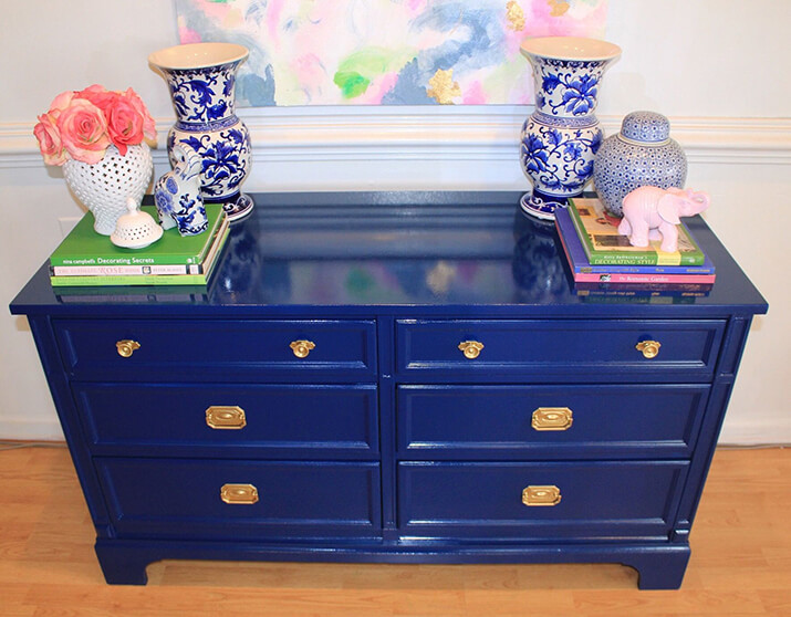 Blue lacquer chest of drawers with china vases and gold hardware.