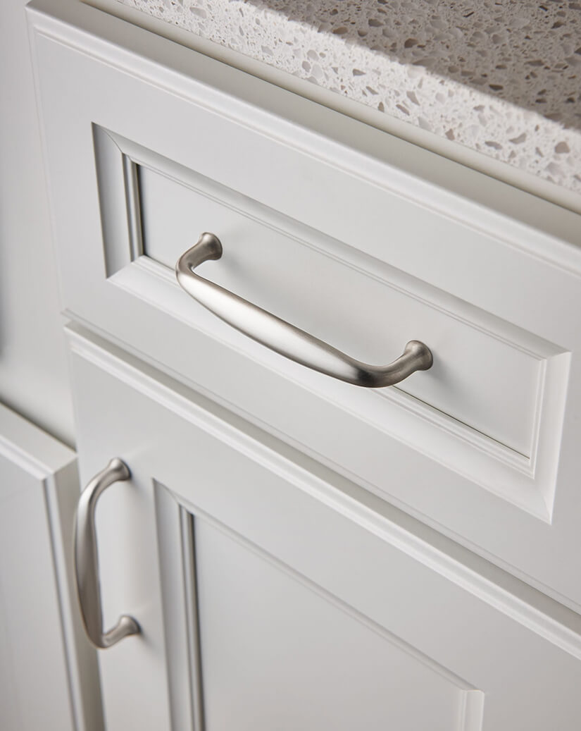 Brushed nickel cabinet and drawer pulls in white kitchen.