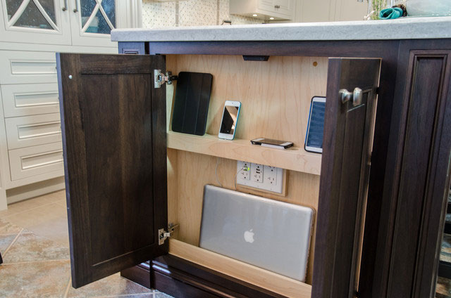 Charging station hidden in kitchen cabinets with shelf to hold devices.