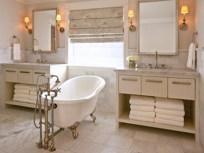 One of many classic clawfoot bathtub styles in a light and airy bathroom with stone tile.