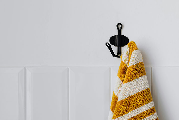 Yellow and white striped towel hanging on black hook.