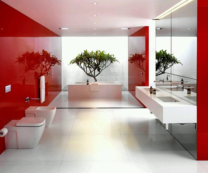 Clean white and red bathroom that looks out onto a private courtyard.