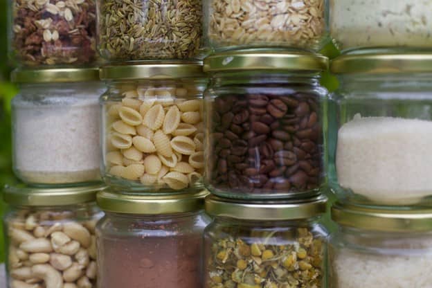 Clear jars of dry goods in a pantry.