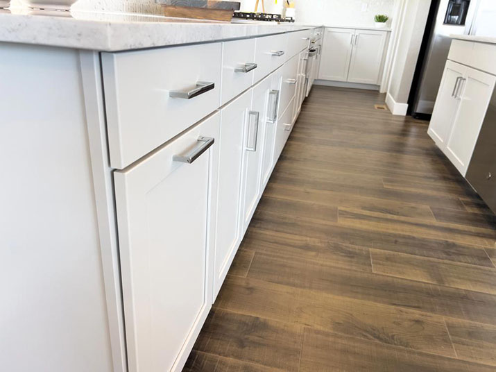 Close up view of lower kitchen cabinet base showing toe kick area.