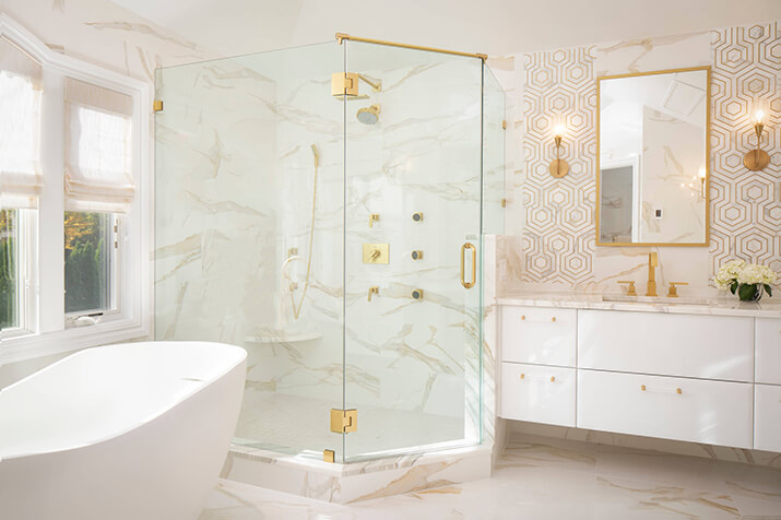 Contemporary master bathroom with high-end gold fixtures and accent wall.
