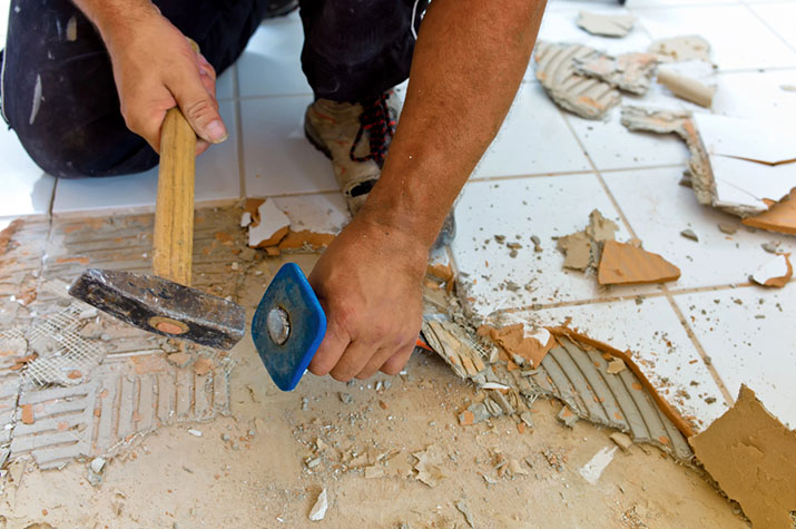 A contractor removing old tile in a kitchen remodel.