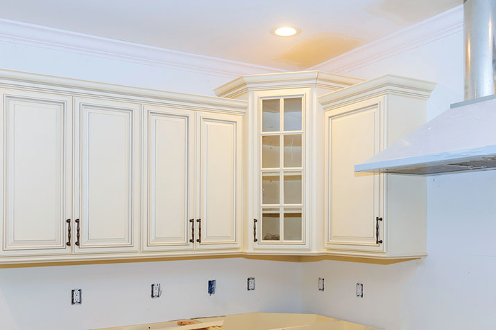 Crown molding added to the top of modern white cupboards.