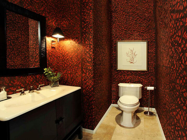 Powder room with dark red patterned wallpaper.