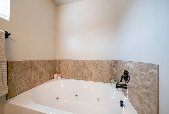 A beige drop-in bathtub in a modern bathroom.