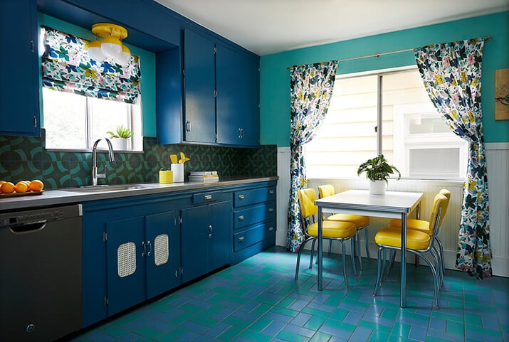 Eclectic, retro kitchen with vibrant blue cabinets and teal flooring and walls.