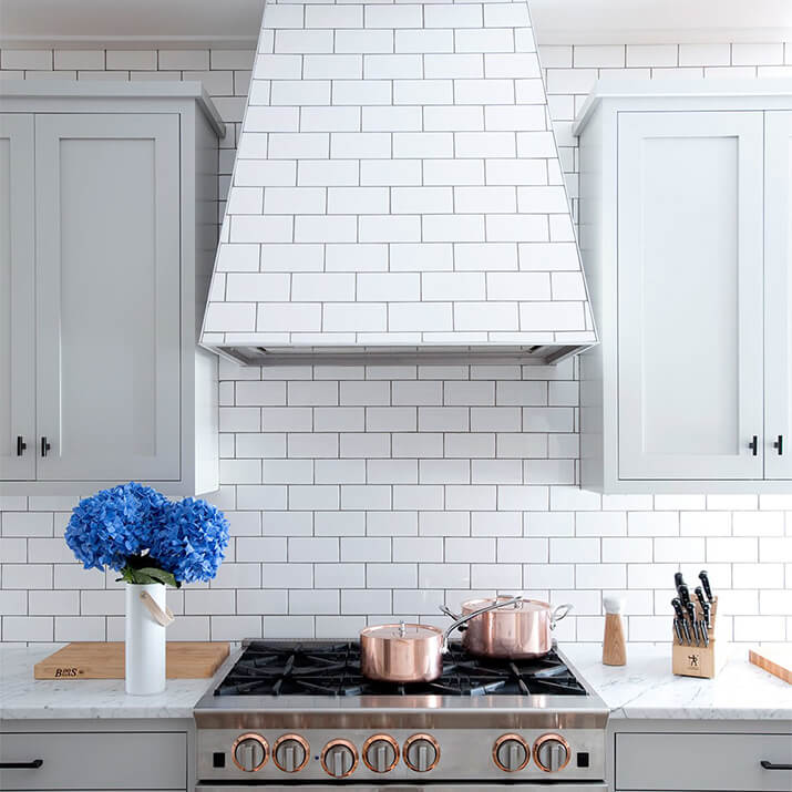 Elegant kitchen hood design with white subway tiles matching the backsplash.