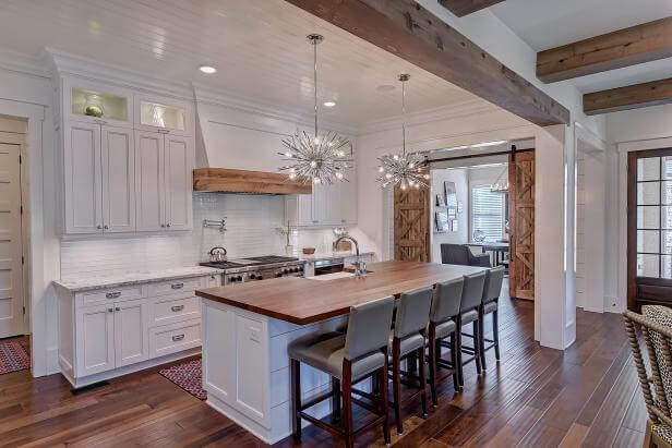Farmhouse kitchen with white shaker-style cabinets and wood countertops.