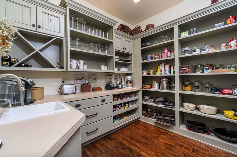 Grey open shelving in large farmhouse pantry with a sink.