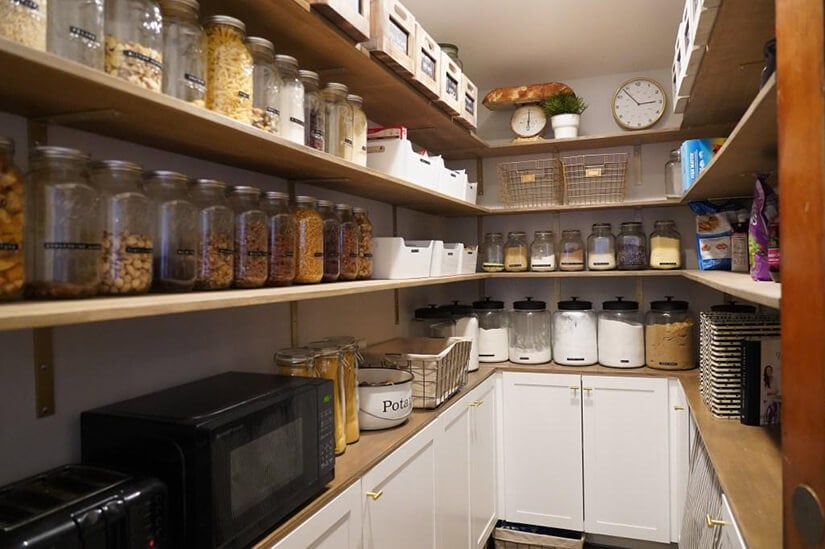 Individually labeled jars and tubs in a farmhouse style pantry.