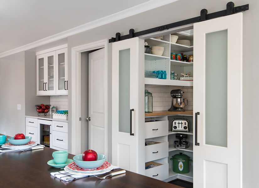 These modern barn doors with frosted glass lead to a farmhouse pantry.
