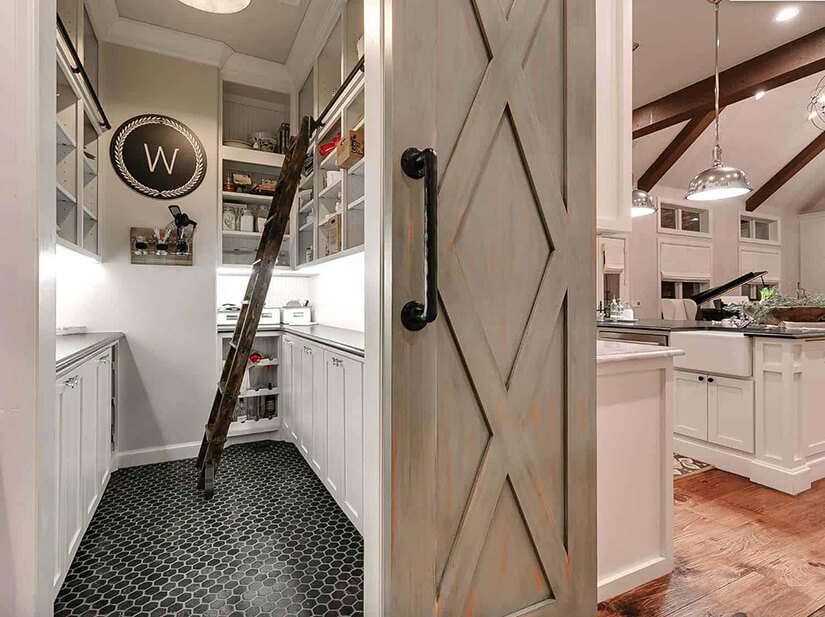 Farmhouse pantry with a rolling ladder to reach upper shelves.