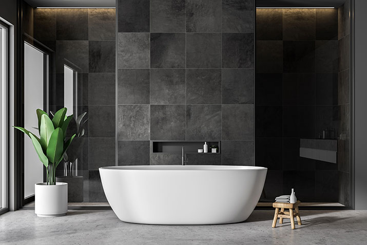 A white freestanding tub in modern black bathroom.