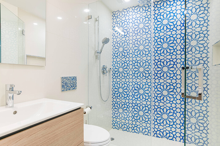 Glass enclosure walk-in shower with blue accent tile shower surround.