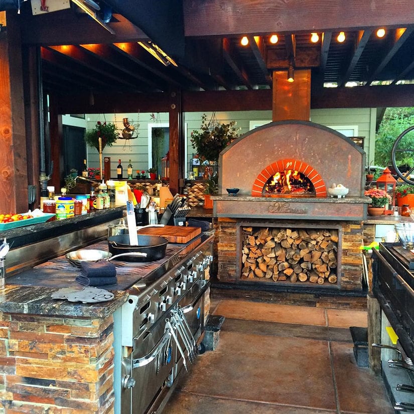 Guy Fieri's outdoor kitchen at home complete with double ovens and a rustic wood oven.