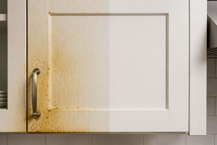 Kitchen cabinet showing heavy grease buildup on one half and a clean degreased surface on the other half.