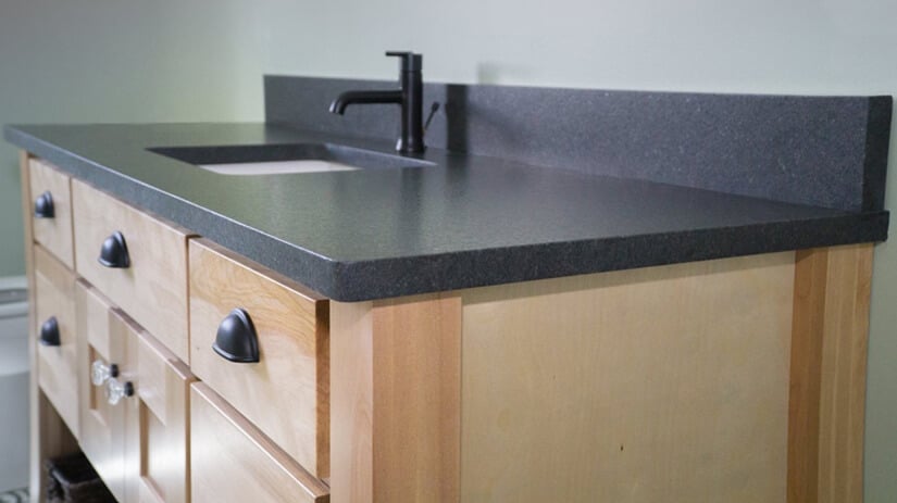 Honed Black Pearl Countertops In Bathroom With Light Wood Cabinets 