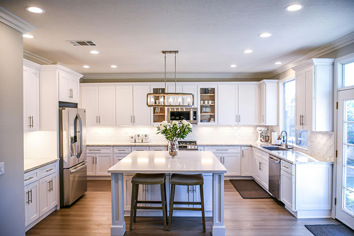 Island with two stools in a white, modern kitchen.