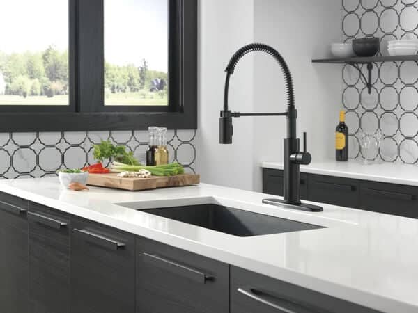 Kitchen with black cabinets and white countertops with a black sink faucet.
