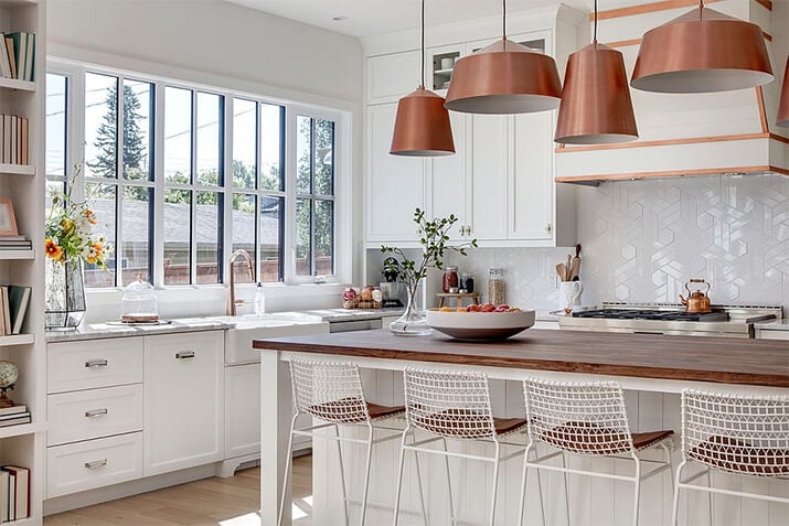 Kitchen boasting natural lighting with white cabinets, wood countertops, and metal accents.