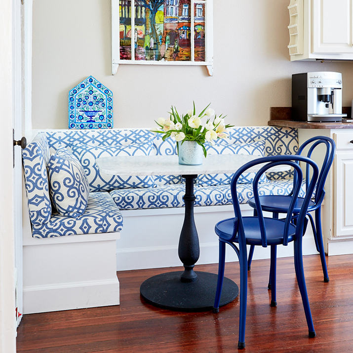 Kitchen nook with metal chairs and bench seating and cushions and pillows.