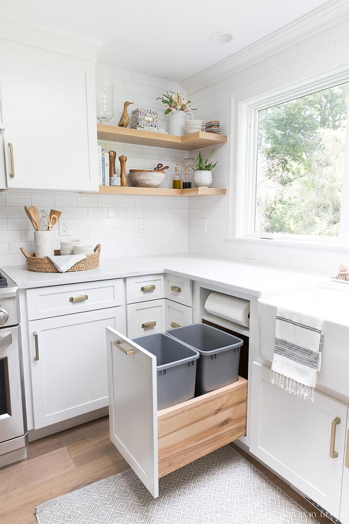 Kitchen with white counters and cabinets and a built-in trash can.