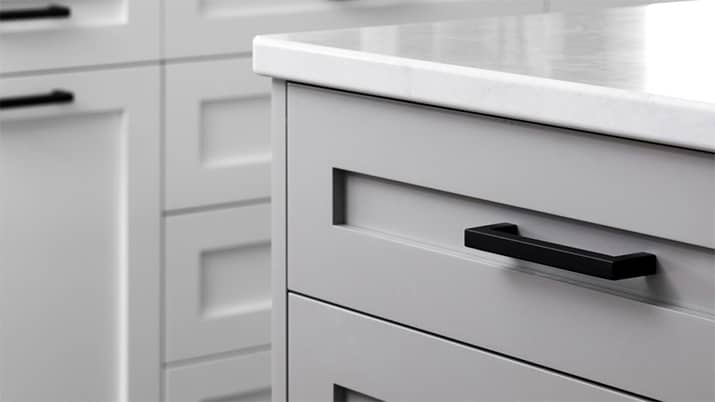 Kitchen with white countertops and gray cabinets with black bar pulls.