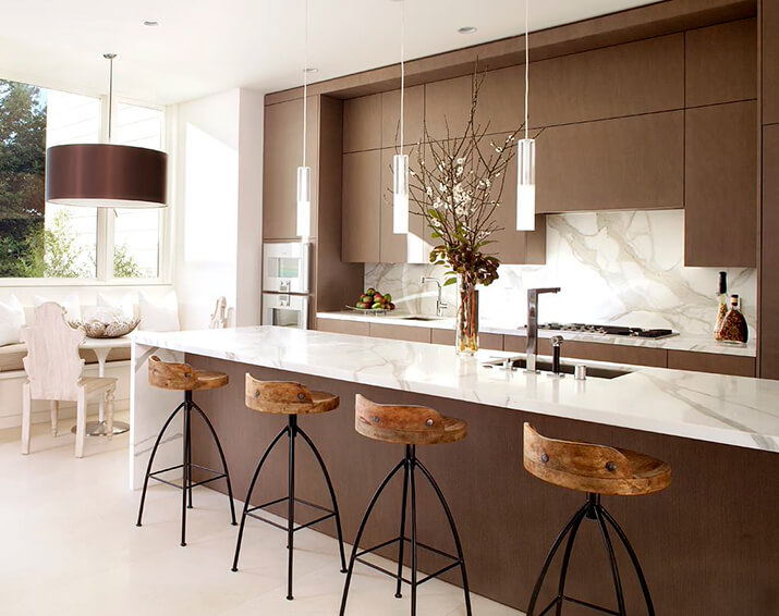 Kitchen with wood flat-panel cabinets, marble countertops, and stone slab backsplash.