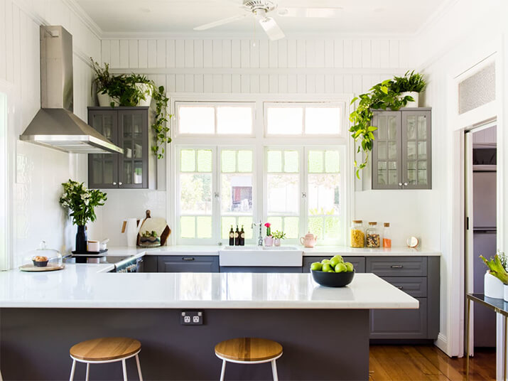 L-shaped kitchen with greenery above kitchen cabinets.