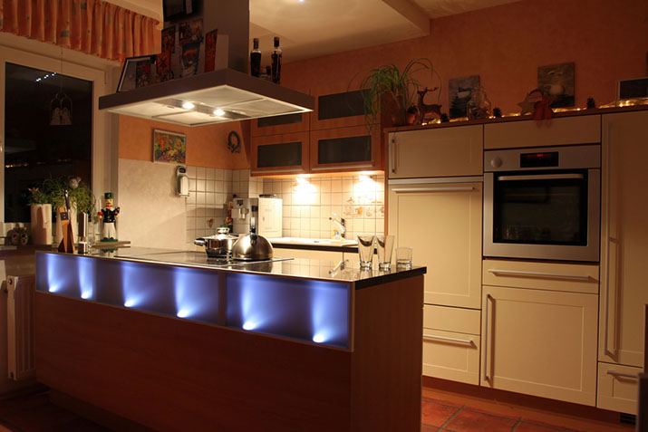A kitchen with multiple layered lighting styles.