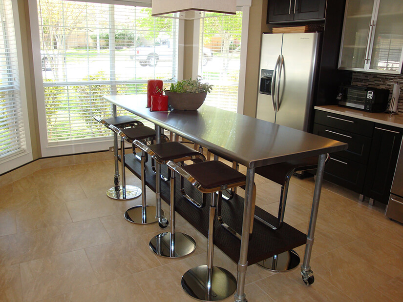 Long stainless-steel prep table as kitchen island with seating
