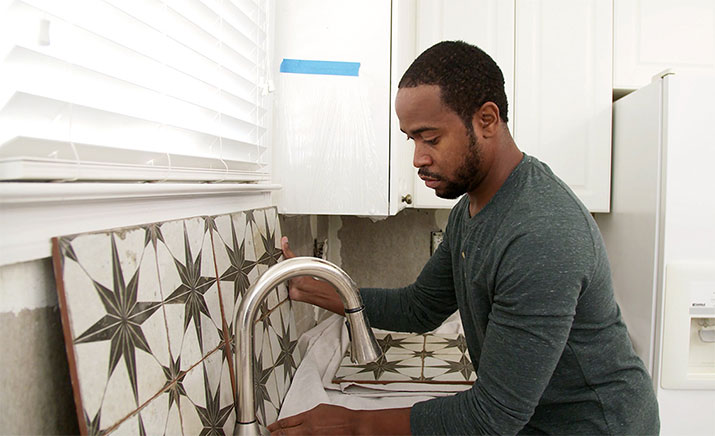 Man pre-laying backsplash tile in kitchen.