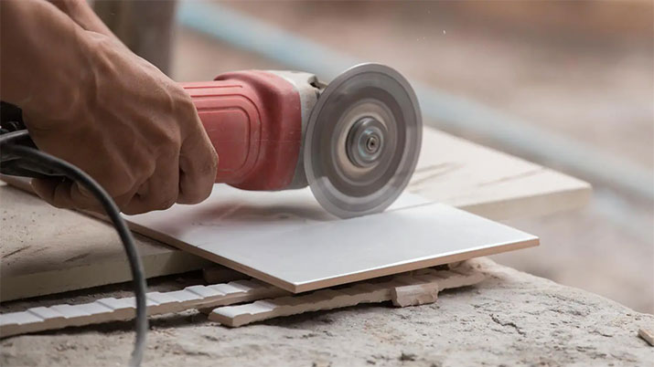 Man using a hand saw to cut tile.