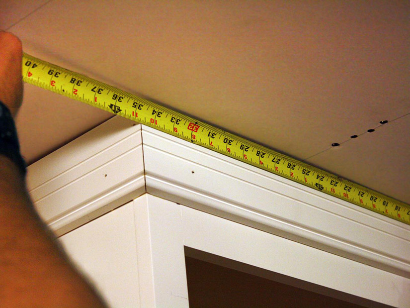 Measuring the front of a crown molding piece in the kitchen.