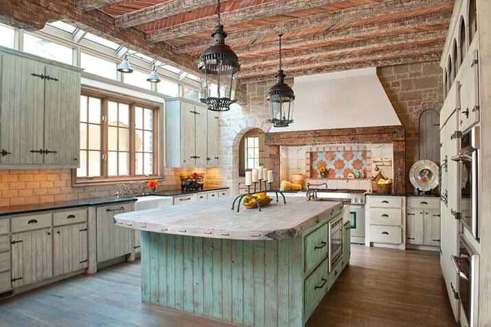 Mediterranean kitchen with distressed cabinets, soapstone countertops, and multicolored backsplash.