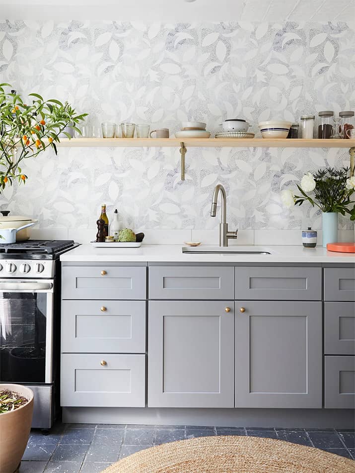 Modern kitchen with gray lower shaker cabinets with knobs.