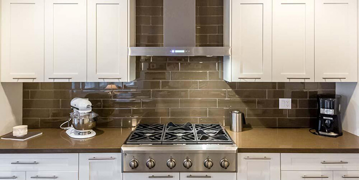 Modern stainless steel kitchen hood design over a gas range.