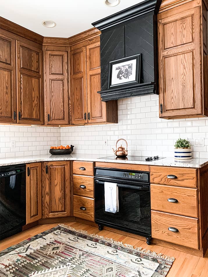 Kitchen with oak cabinets with black appliances and a black range hood.