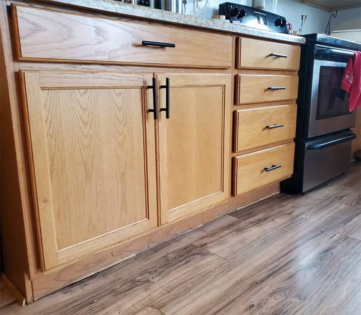 Oak wood kitchen cabinets with modern black hardware.